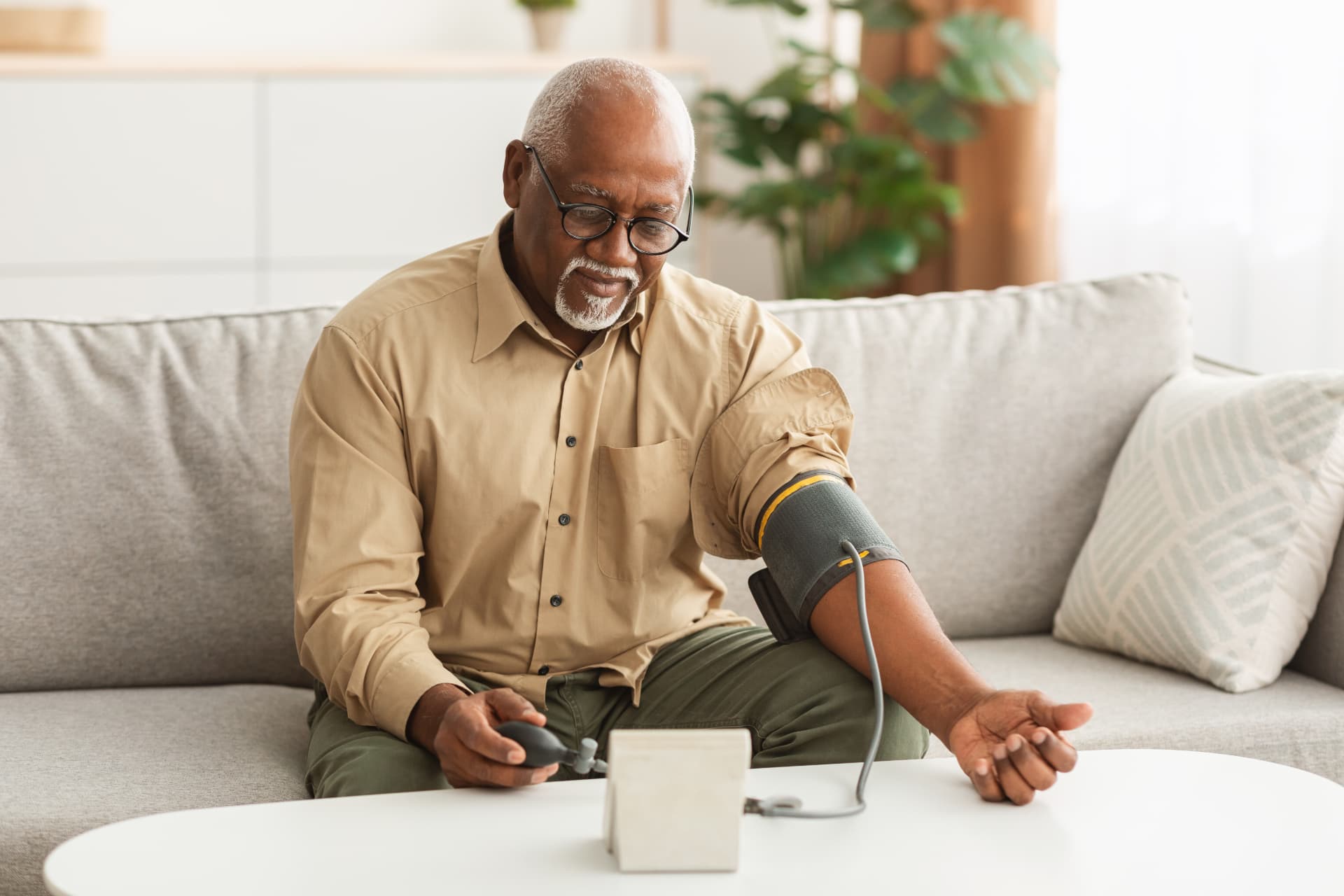 A veteran checking his blood pressure at home with an arm cuff monitor
