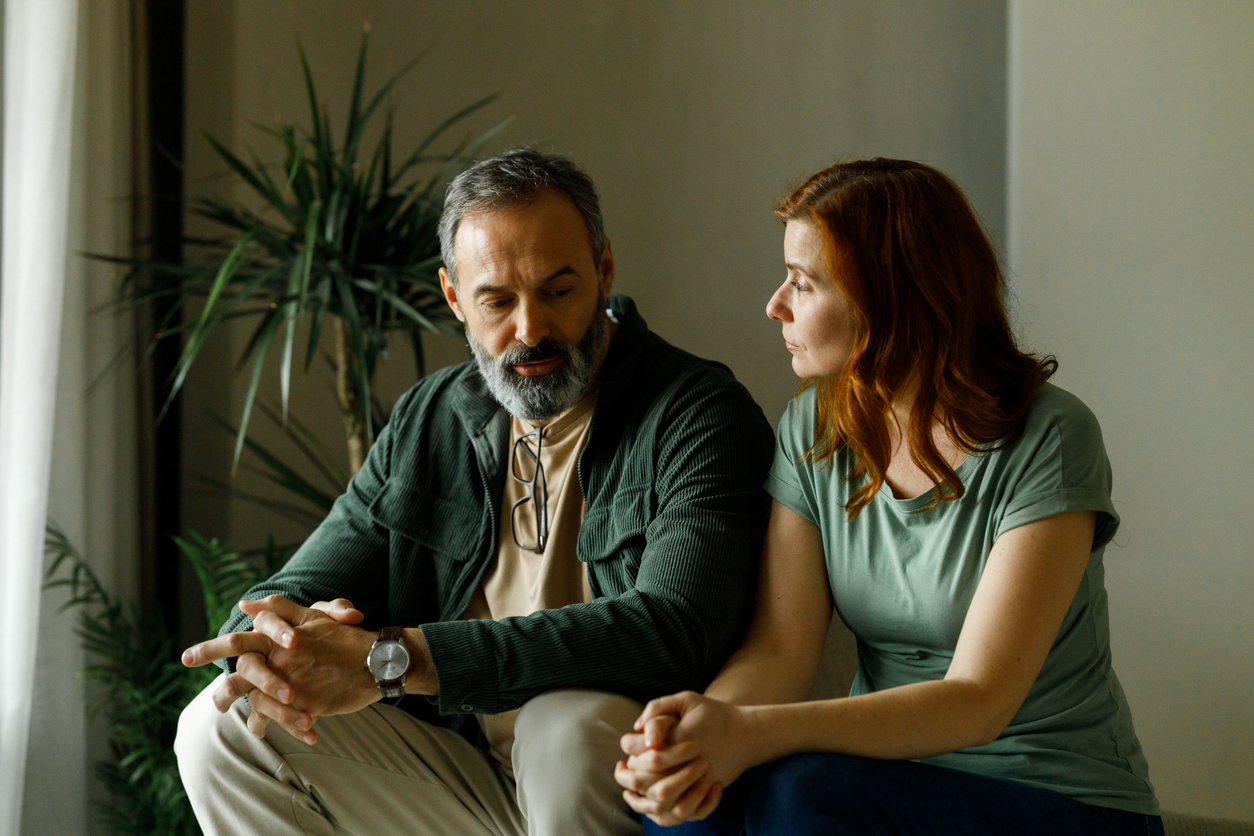 Couple sitting together in quiet conversation, appearing withdrawn
