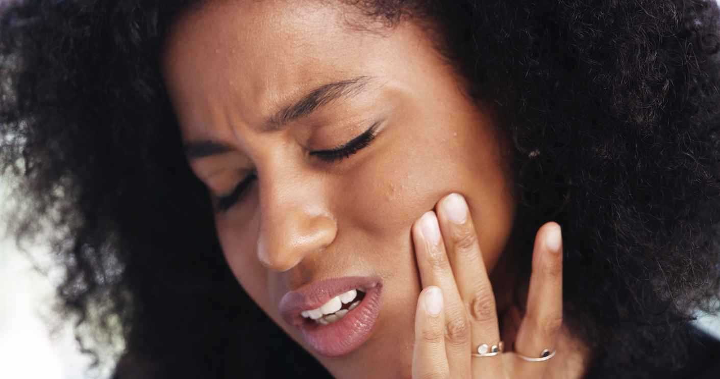 Woman veteran holding her jaw in pain from TMJ dysfunction