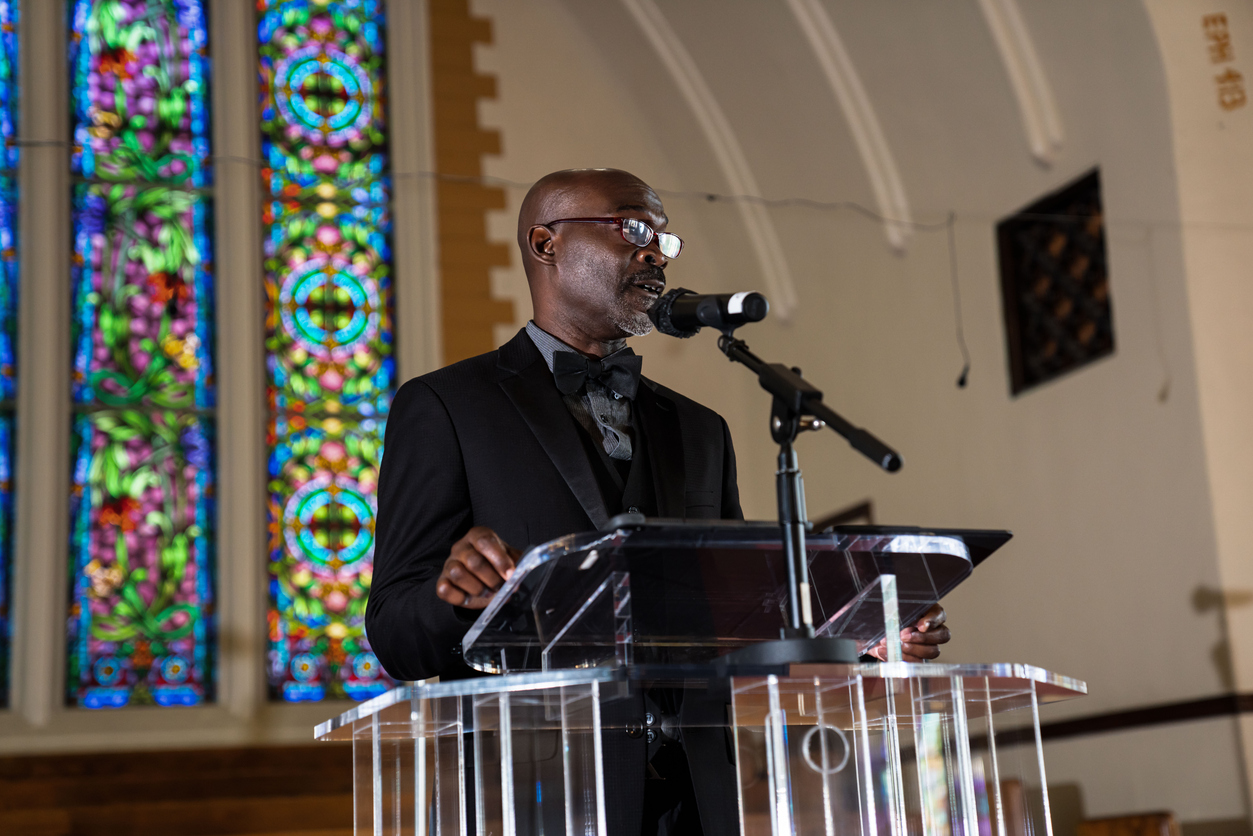 A pastor speaking from a pulpit during a church service