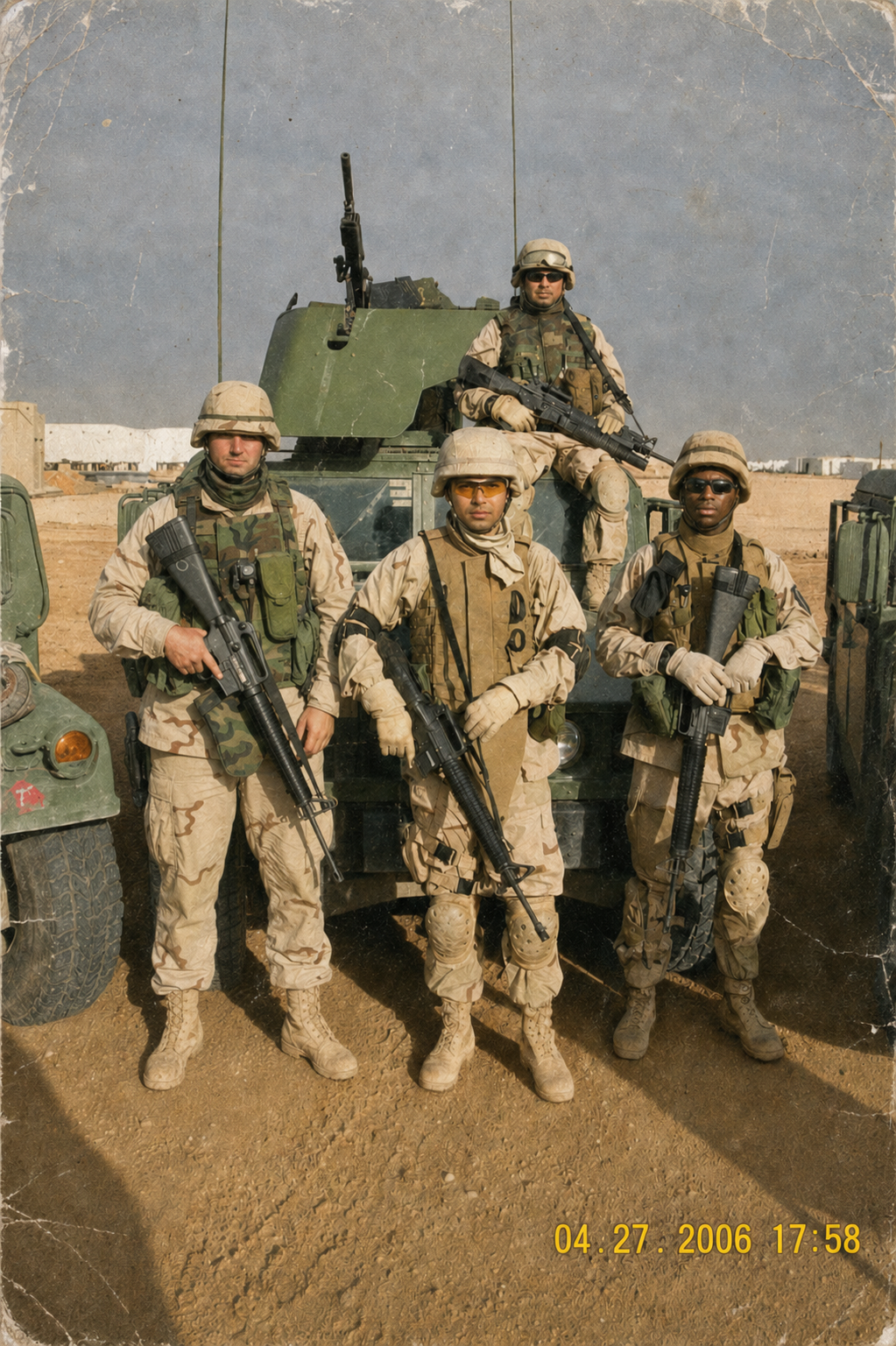 Four U.S. soldiers in desert camouflage standing with weapons in front of an armored vehicle in Iraq